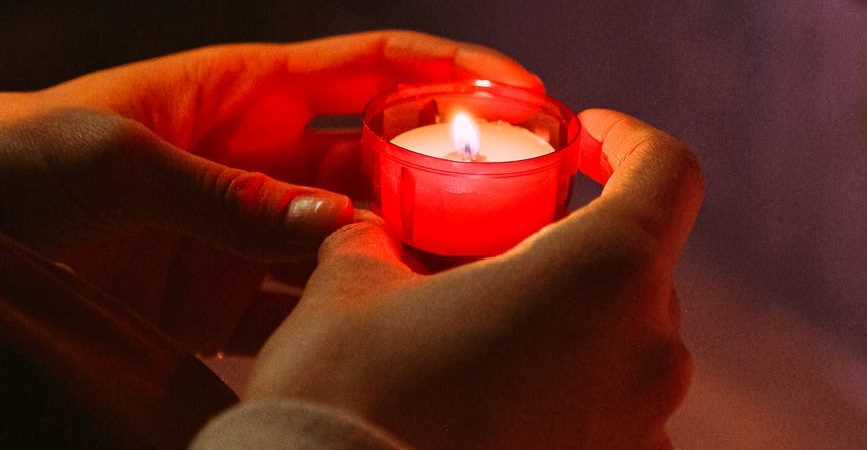 person holding red candle in a dark room